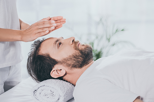 partial view of calm bearded receiving reiki treatment and looking up